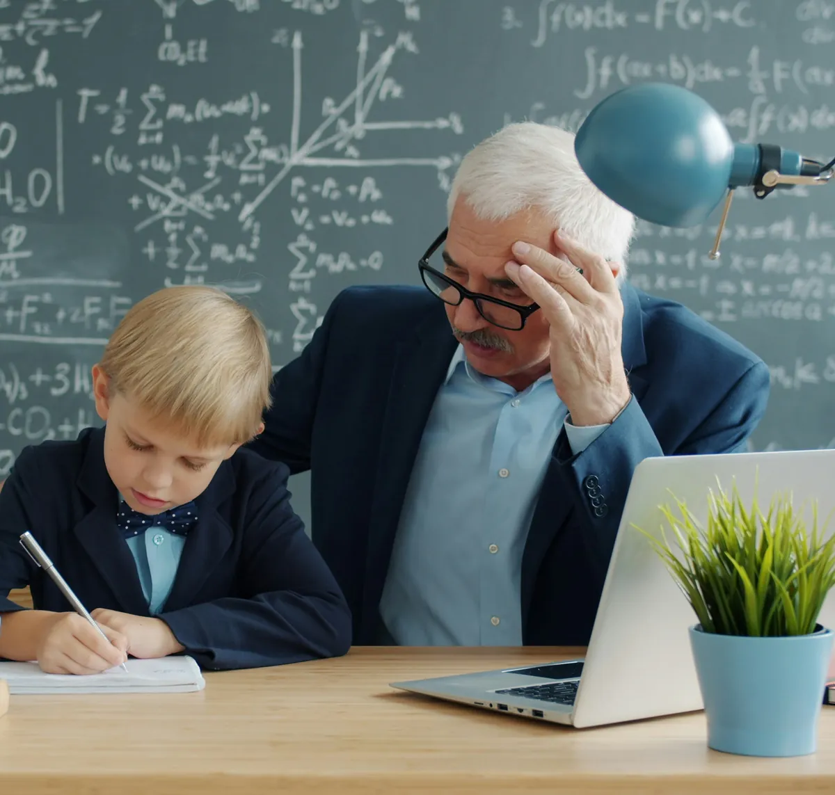 Tutor helping a young student with his notes at a desk